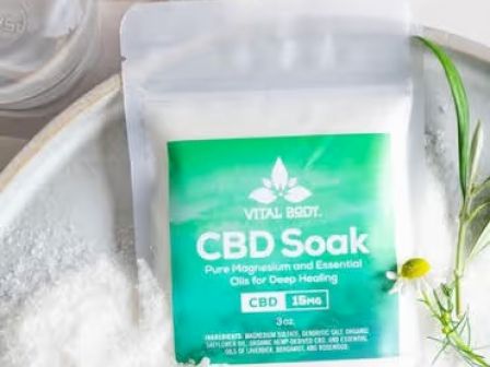The image shows a package labeled "Vital Body CBD Soak," containing magnesium and essential oils for deep healing, placed on a bowl of salt.