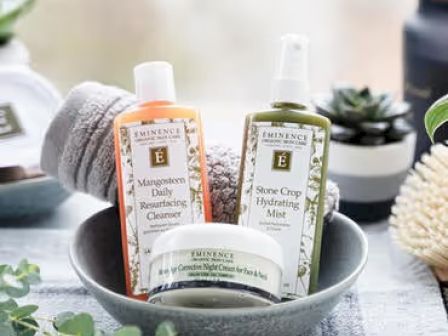 Skincare products in a bowl: cleanser, hydrating mist, and night cream. Decorative items and greenery surround them.