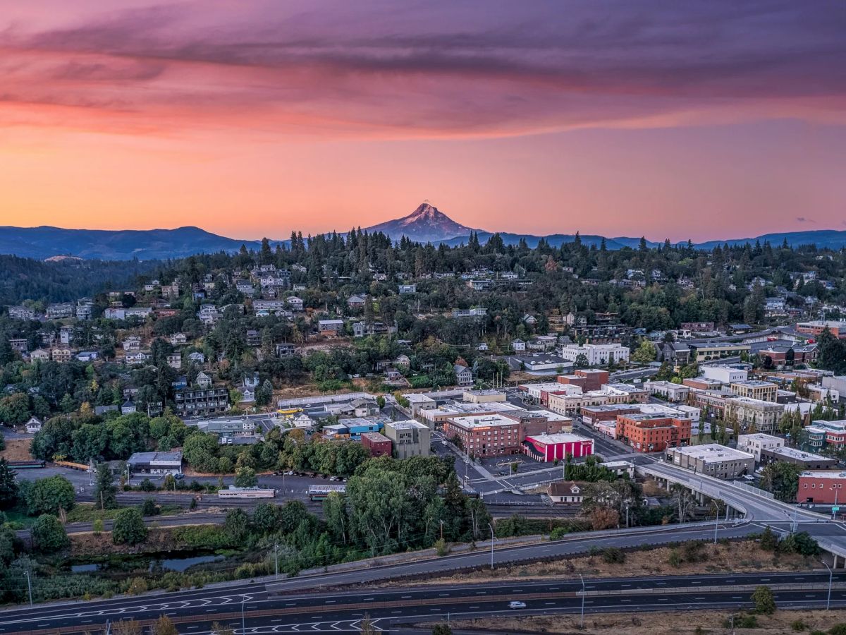 A picturesque town at sunset with a mountain in the background and a network of roads in the foreground, creating a serene landscape.