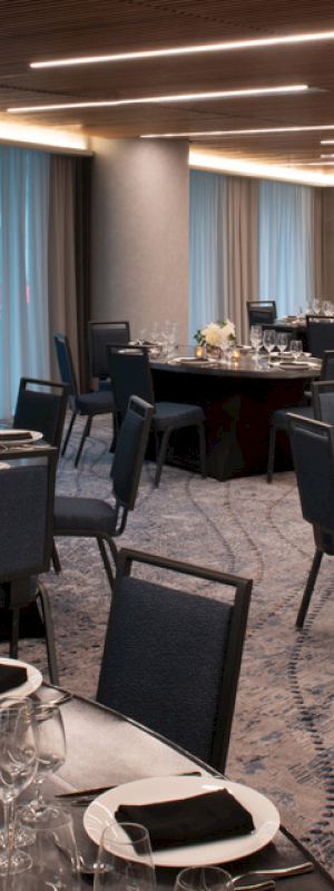 A banquet hall with round tables set for an event, featuring elegant tableware and floral centerpieces.